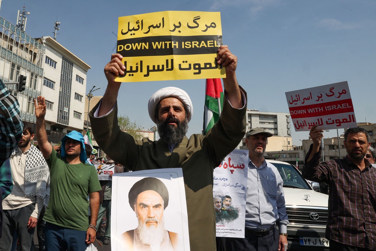EUA e Reino Unido provocam conflitos entre Irã e Israel desde os anos 1950 Manifestante iraniano com foto do aiatolá Ruhollah Khomeini durante protesto contra os ataques israelenses contra o Irã (Foto: Atta KENARE / AFP)
