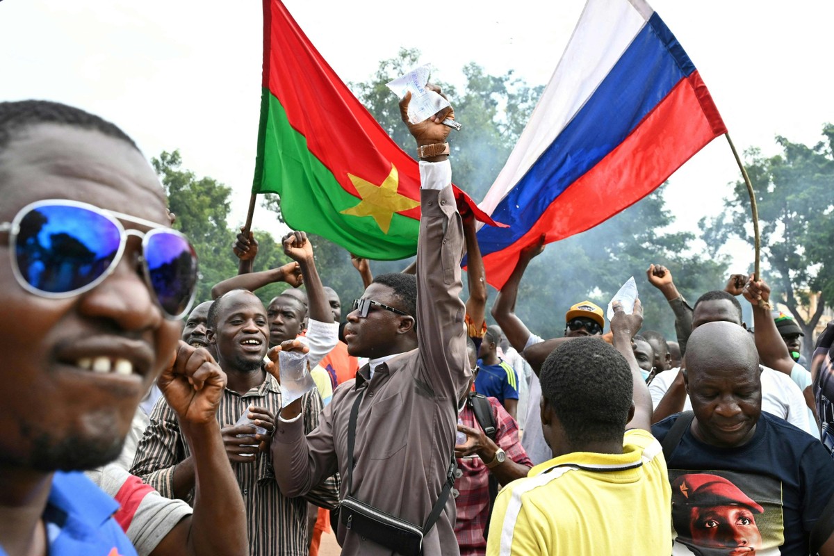 Apoiadores do novo líder da junta de Burkina Faso, Ibrahim Traore, seguram bandeiras nacionais de Burkina Faso e da Rússia durante uma manifestação perto da sede nacional de rádio e televisão (RTB) em Ouagadougou (Foto: ISSOUF SANOGO/AFP)