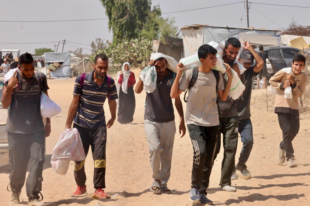 Palestinos carregam ajuda humanitária que receberam em Rafah, no sul da Faixa de Gaza (Foto: AFP)