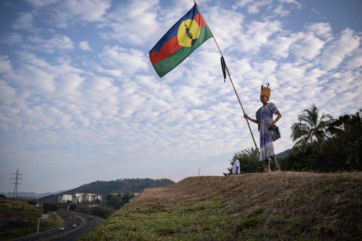 França estabelece acordo histórico para autonomia da Nova Caledônia no Pacífico Sul Mulher com vestido tradicional segura uma bandeira Kanak no distrito de Dumbea, em Noumea, no território francês do Pacífico da Nova Caledônia, em 24 de setembro de 2024 (Foto: Sebastien Bozon/AFP)