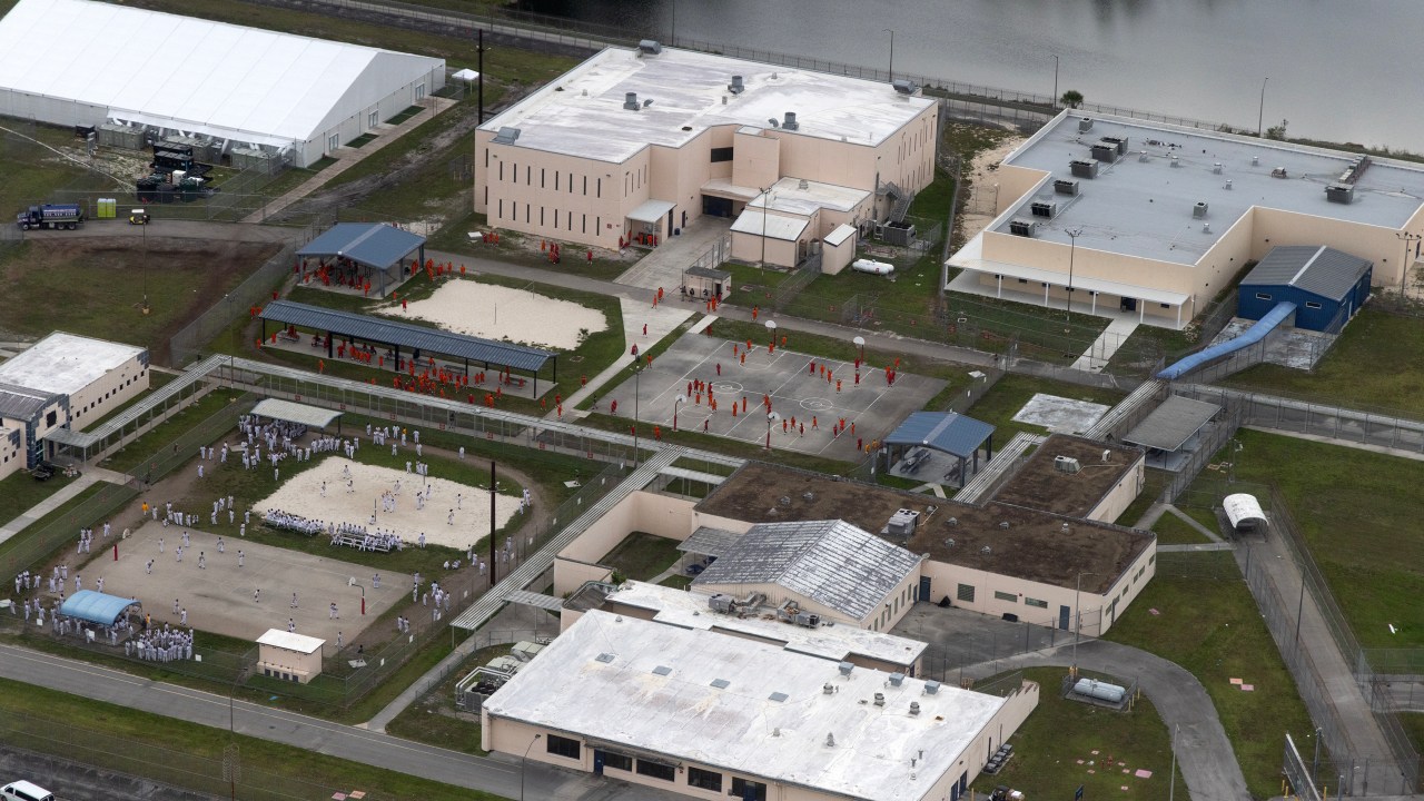 Uma vista aérea de um helicóptero mostra detentos no Krome Detention Center, administrado pelo Departamento de Imigração e Alfândega dos Estados Unidos, em 4 de julho de 2025, em Miami, Flórida. O presidente dos EUA, Donald Trump, esteve presente na inauguração do "Alligator Alcatraz", uma instalação de 5.000 leitos, localizada em um antigo campo de aviação nos pântanos dos Everglades, parte de sua expansão das deportações de migrantes indocumentados. (Foto: Alon Skuy/Getty Images)