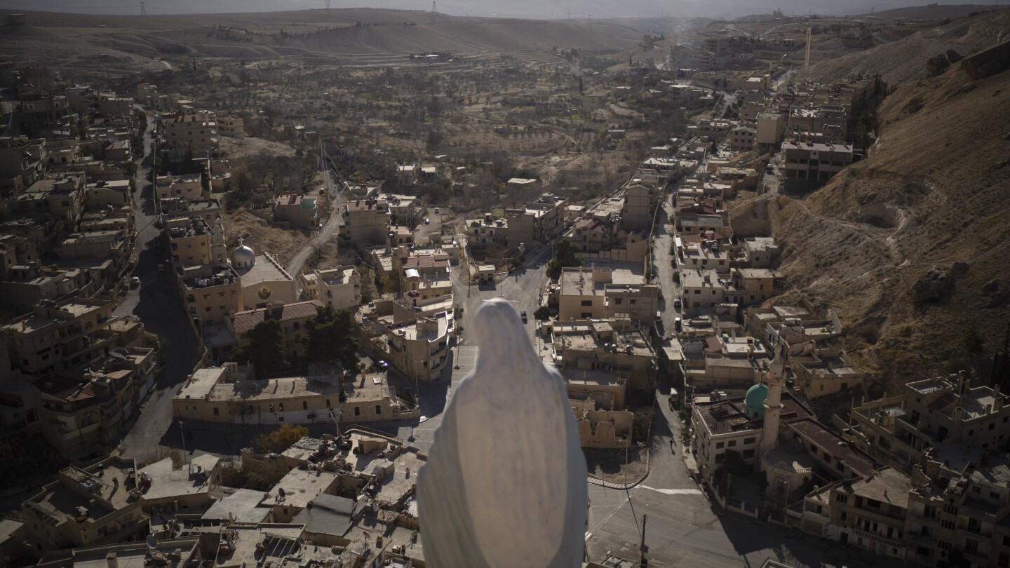 Uma estátua da Virgem Maria fica no topo de um penhasco com vista para as casas de Maaloula, uma vila onde o aramaico ainda é falado, localizada a cerca de 60 km ao norte de Damasco, Síria, 25 de dezembro de 2024. (Foto: AP Photo/Leo Correa, File)