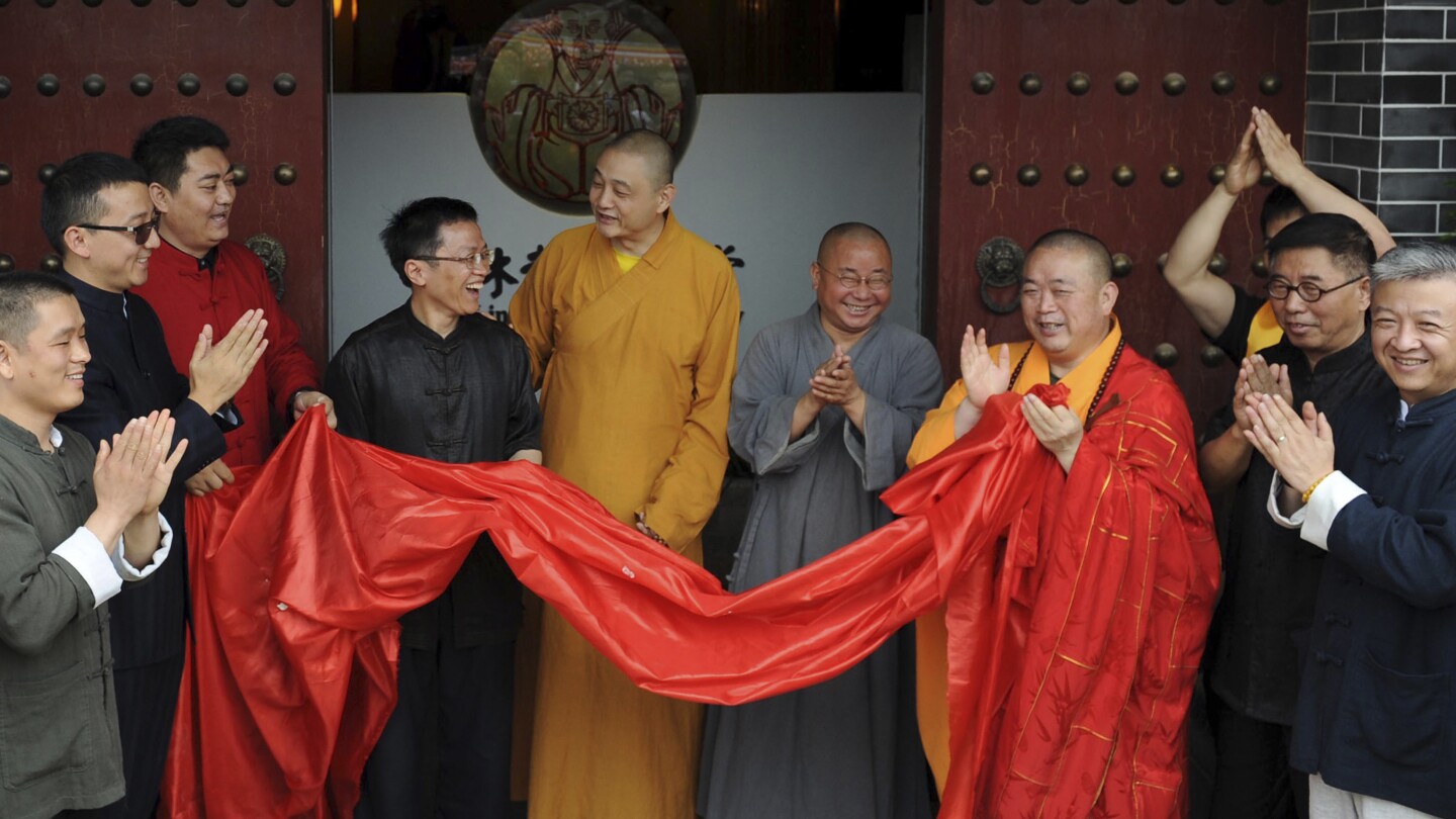 Shi Yongxin, terceiro da direita, em roupas amarelas e vermelhas, abade do Templo Shaolin, participa da cerimônia de abertura de um centro zen urbano chamado Shaolin Chan Hall em Xi'an, na província de Shaanxi, noroeste da China, no domingo, 28 de junho de 2015. (Foto: Chinatopix via AP, arquivo)
