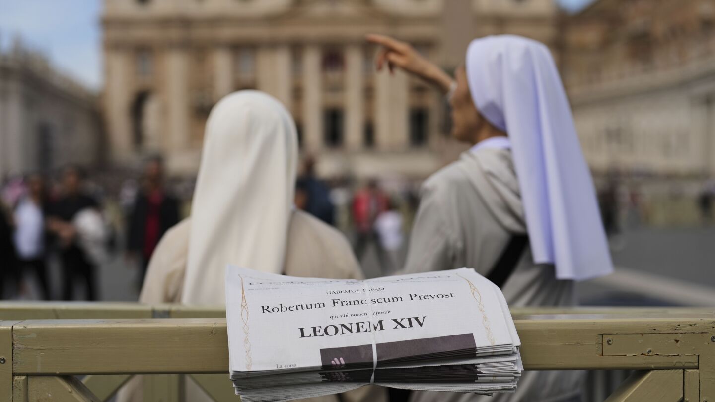 Freiras estão ao lado de cópias do jornal L'Osservatore Romano com manchetes em latim do Papa Leão XIV no Vaticano, na sexta-feira, 9 de maio de 2025, um dia após sua eleição como o primeiro papa norte-americano. (Foto: AP Photo/Francisco Seco, arquivo)