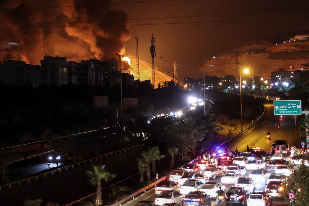 Solidariedade se destaca em meio ao sofrimento causado pela guerra Incêndio em depósito de combustível no norte de Teerã, provocado por bombardeio israelense (Foto: ATTA KENARE / AFP)
