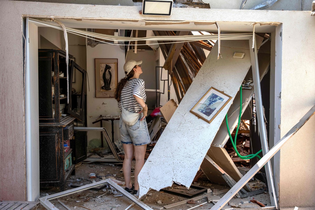 Irã ataca Israel com mísseis após ofensiva dos EUA e deixa 23 feridos Moradora observa danos à casa após ataques do Irã a bairro de Tel Aviv (Foto: MAYA LEVIN / AFP)