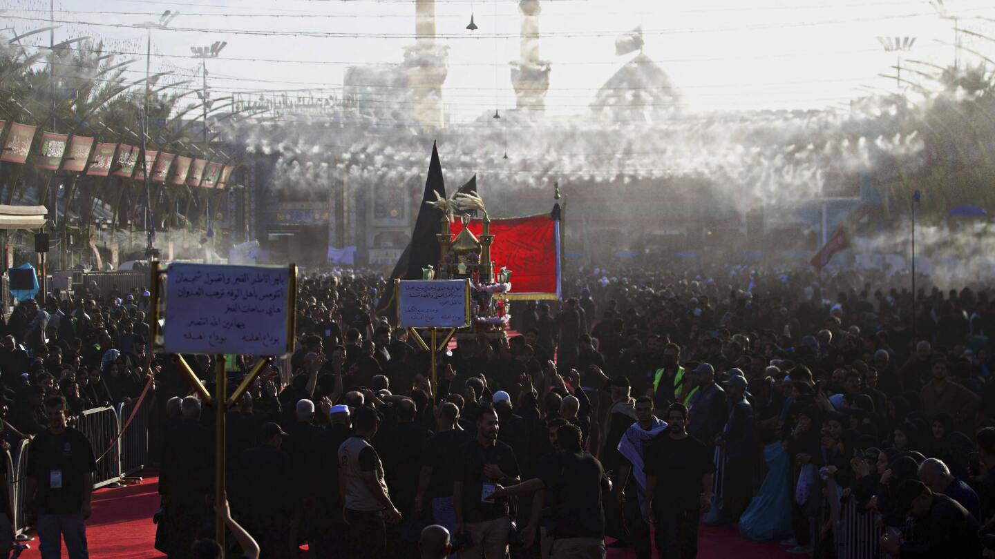 Fiéis xiitas se reúnem entre os santuários sagrados de Imam Hussein e Imam Abbas, ao fundo, durante Muharram, um período de luto para os xiitas, em Karbala, Iraque, sábado, 5 de julho de 2025. (Foto: AP Photo/Anmar Khalil)