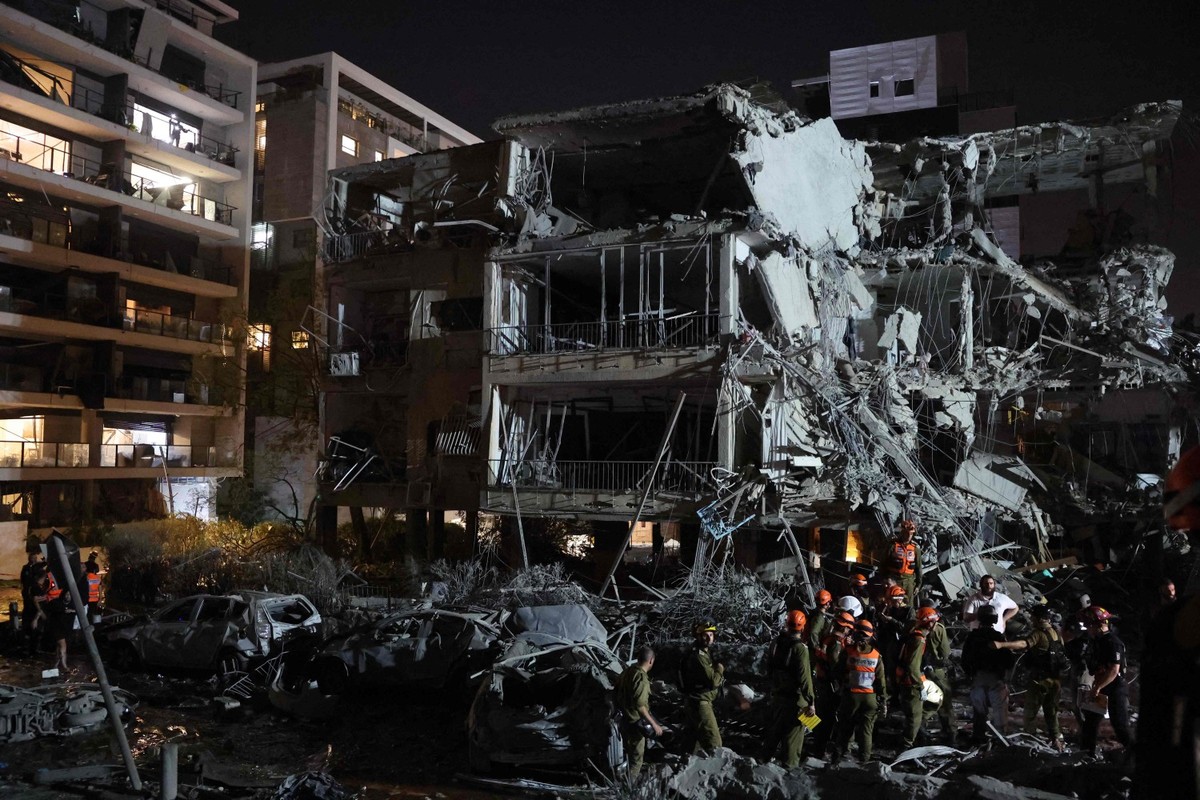 Socorristas buscam feridos após míssil do Irã atingir prédio em Tel Aviv (Foto: Gil COHEN-MAGEN / AFP)