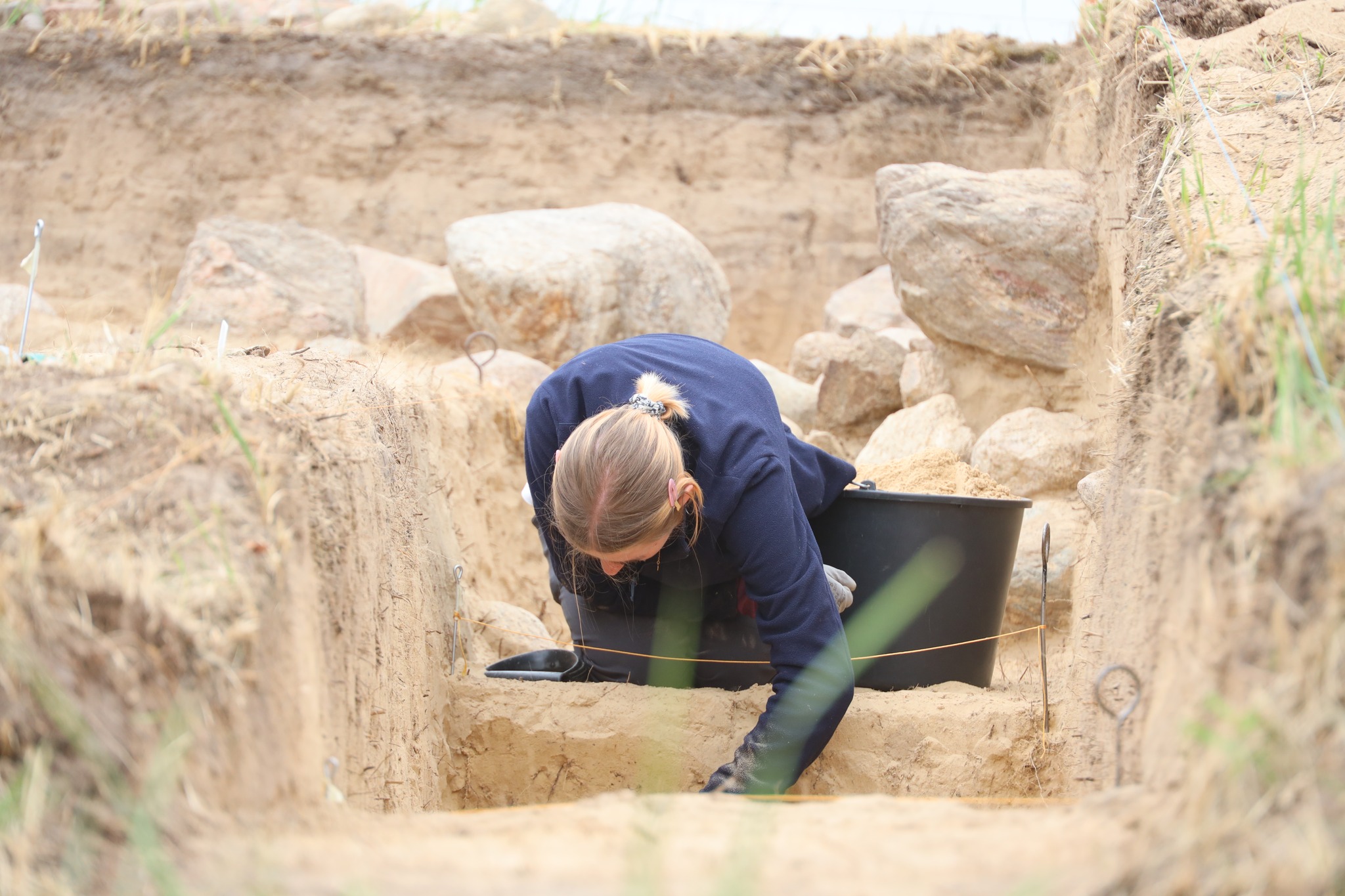 Arqueólogos descobrem tumbas megalíticas de 5.500 anos na Polônia Um arqueólogo escavando o recinto de pedra da tumba. (Foto: Complexo de Parques Paisagísticos do Voivodato de Wielkopolska)