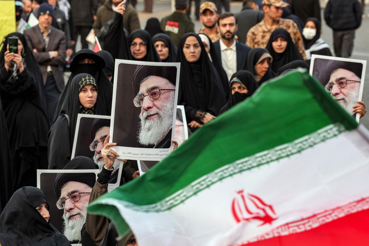 Irã vive crise sem precedentes e futuro do regime de Khamenei se torna incerto Iranianas levam retratos de Khamenei em protesto anti-Israel em Teerã (Foto: AFP)