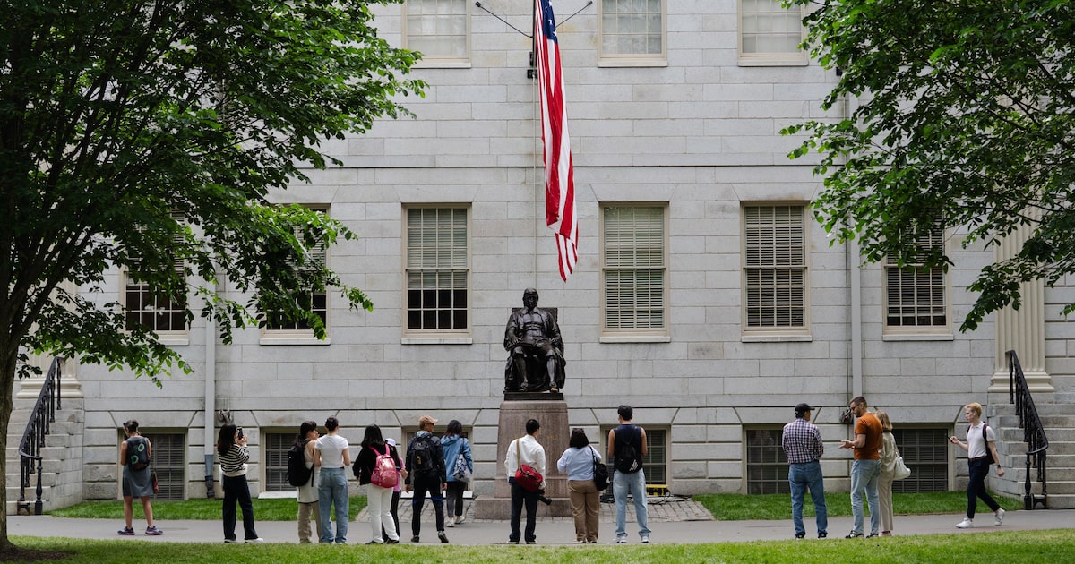 Alunos da Universidade de Harvard tiram fotos com a estátua de John Harvard, em Cambridge (Foto: Sophie Park /NYT)
