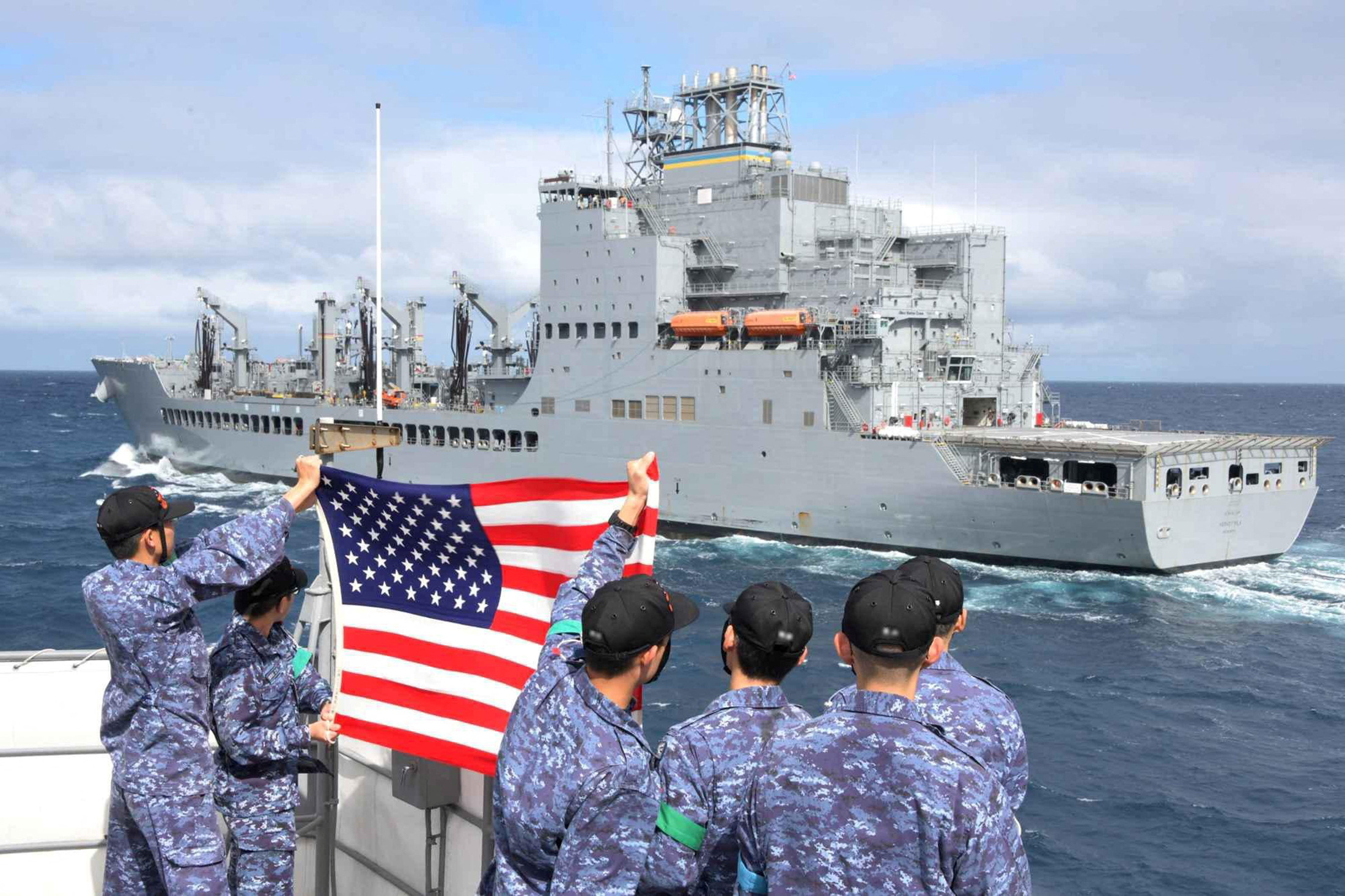 Tripulantes do contratorpedeiro de mísseis guiados JS Shimakaze da Força de Autodefesa Marítima Japonesa seguram uma bandeira dos EUA em direção ao navio petroleiro USNS Harvey Milk da Marinha dos EUA durante um exercício na área de operação de Virginia Capes (VACAPES), no Oceano Atlântico, em 24 de setembro de 2024. (Foto: LaShawn Sykes/Marinha dos EUA/Divulgação via REUTERS)