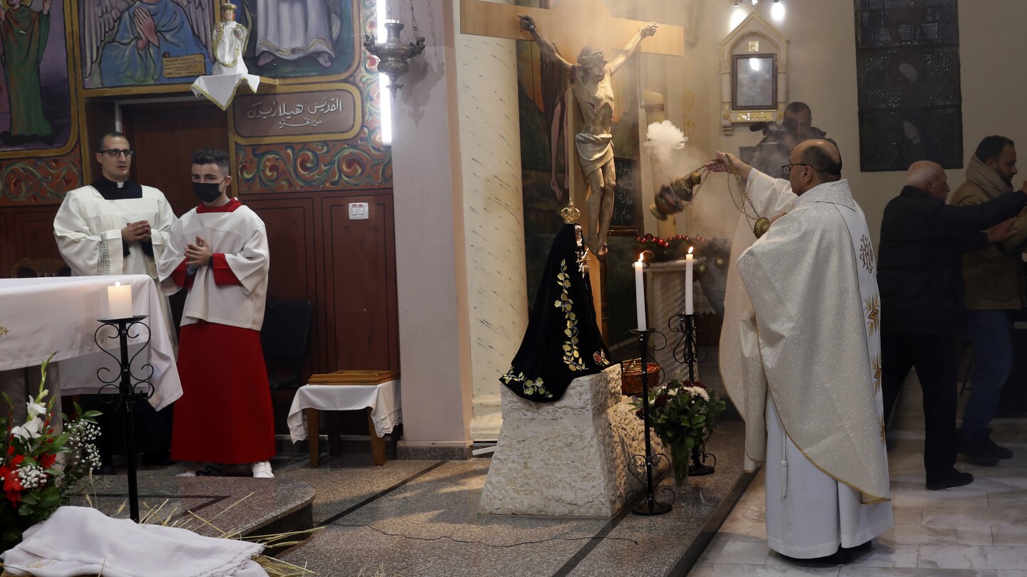 Fr. Gabriel Romanelli, sacerdote católico da paróquia latina da Faixa de Gaza, à esquerda, reza durante a missa de Natal à meia-noite na Igreja Católica da Sagrada Família em Deir Al Latin, na Cidade de Gaza, em 24 de dezembro de 2021. (Foto: AP Photo/Adel Hana, File)