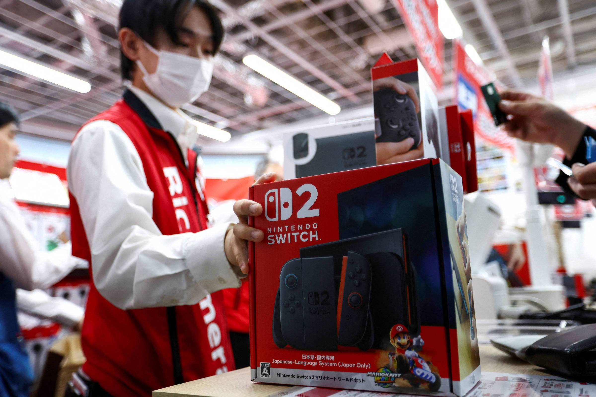 Nintendo Switch 2 some da Amazon dos EUA após vendas não autorizadas de jogos Vendedor segura um Nintendo Switch 2 (Foto: Issei Kato/REUTERS)